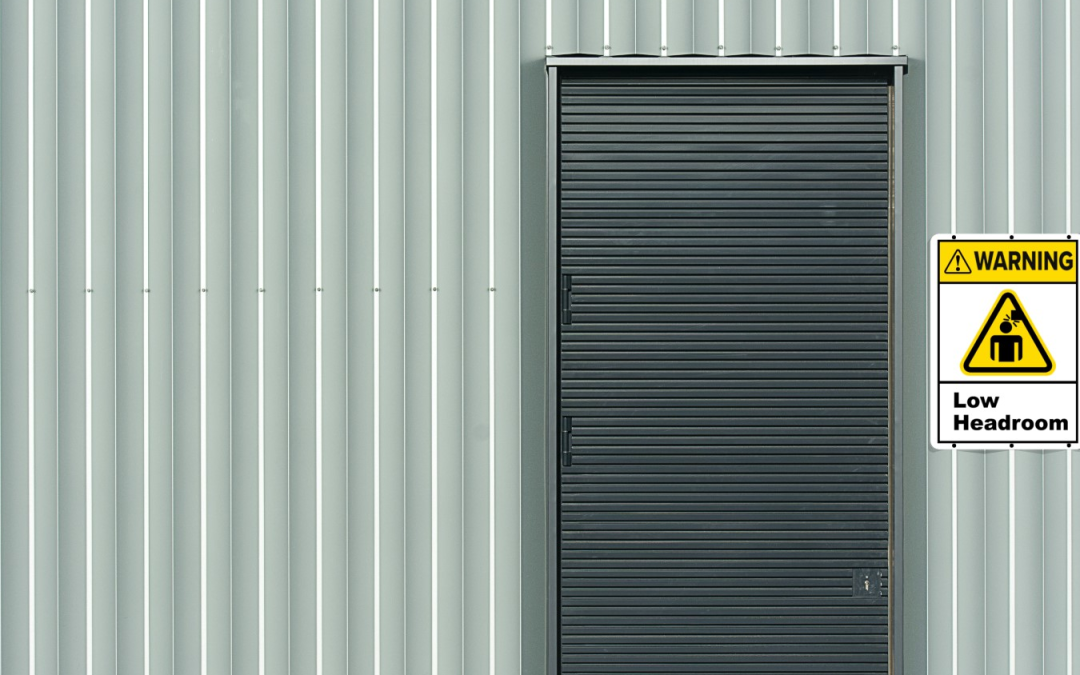 Image of tall roller shutter door allowing entry, but warning of low headroom inside.